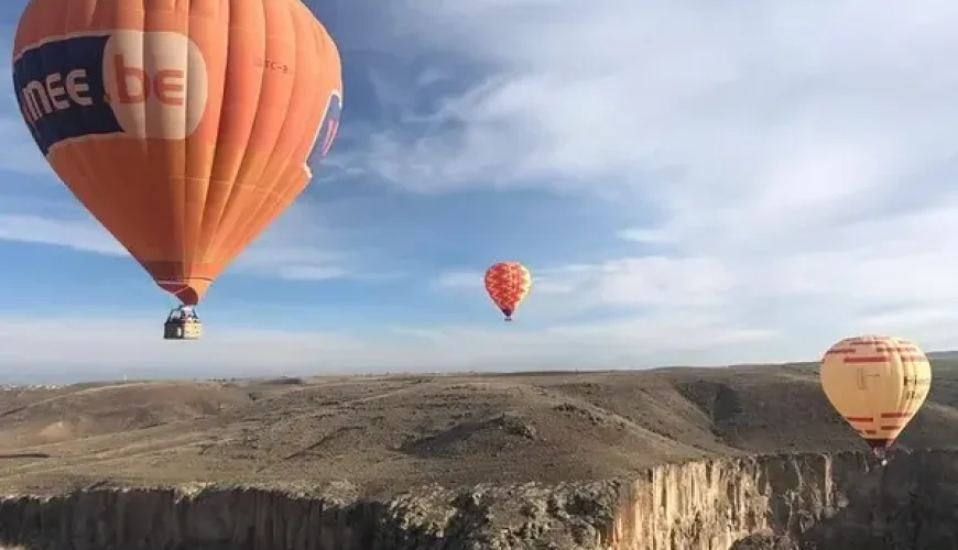 Hot air balloon soaring over Ihlara Valley at sunrise