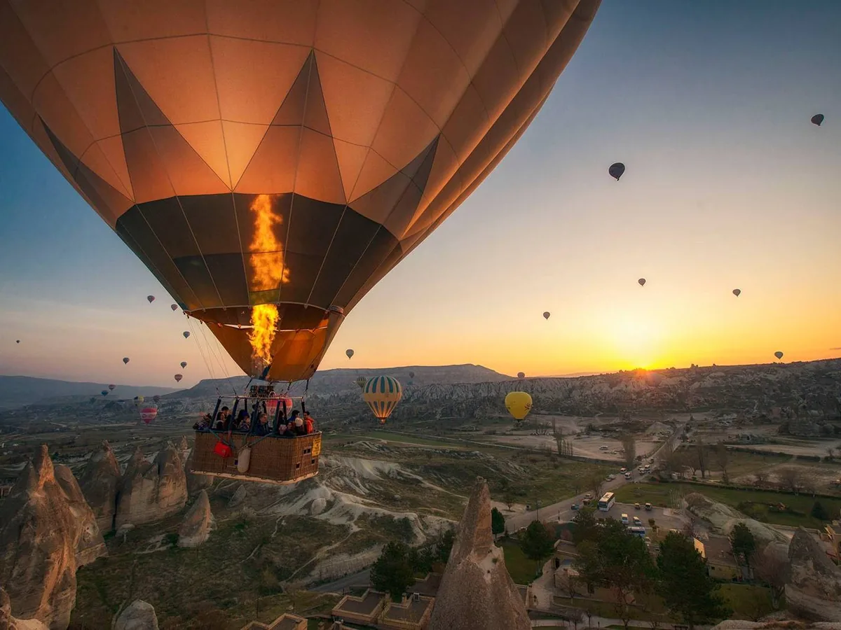 Hot air balloon basket floating over Cappadocia at sunrise