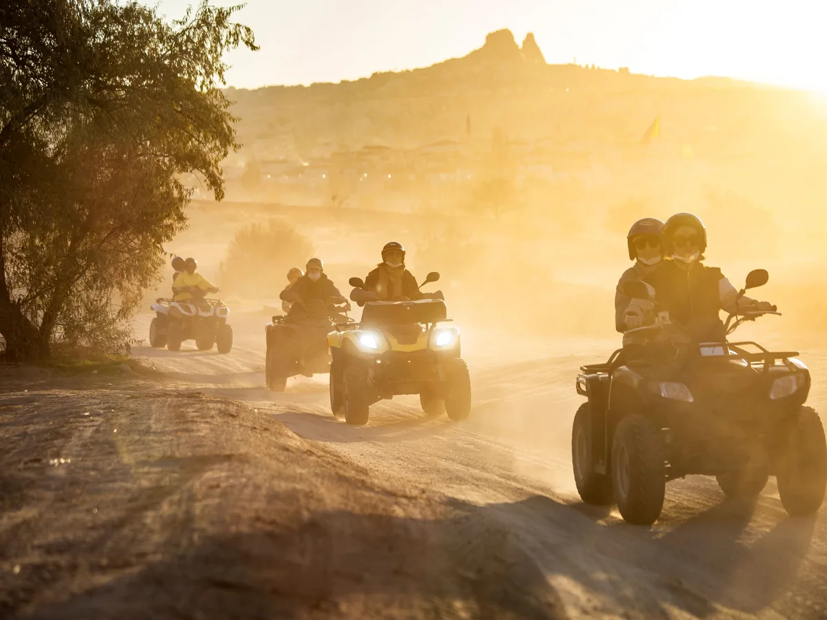 Travelers riding quad bikes on a sunlit Cappadocia trail at golden hour