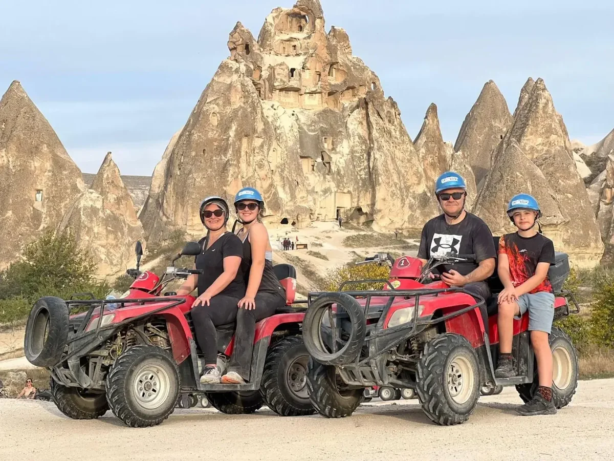 Family group posing on quad bikes in front of Cappadocia rock formations