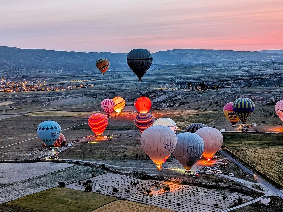 Hot air balloons rising across Cat Valley during a colorful Cappadocia sunrise