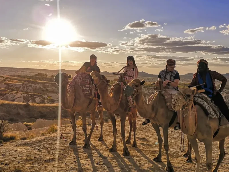Camel riding group enjoying golden sunset views across Cappadocia