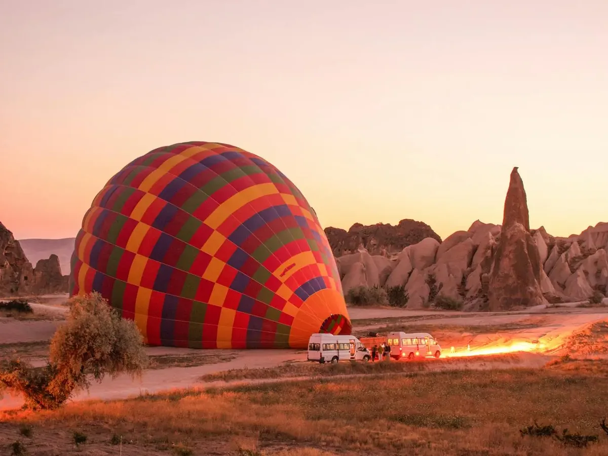 Hot air balloon preparing for a sunrise flight among the rock formations of Cat Valley