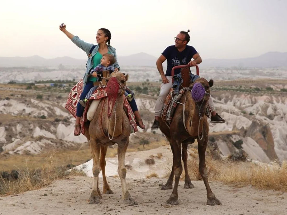 Travelers riding camels through the Cappadocia valleys on a daytime camel tour