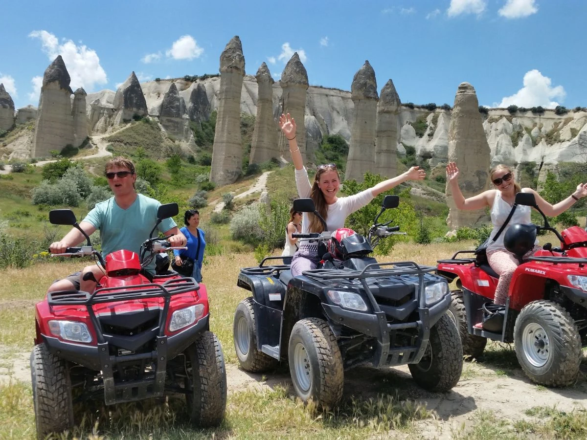 Travelers riding quad bikes beside Cappadocia fairy chimneys