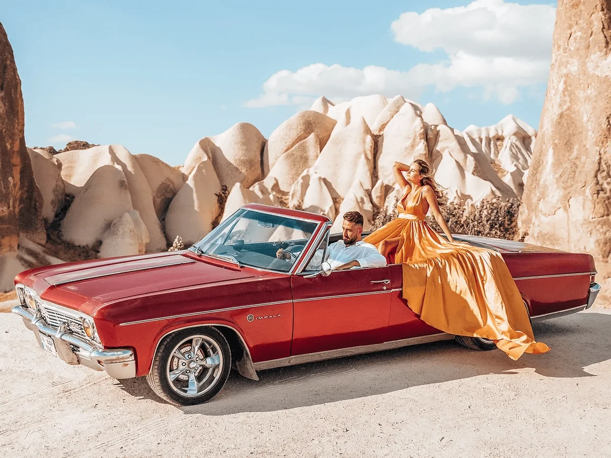 Couple posing with a red vintage convertible during a daytime Cappadocia car tour