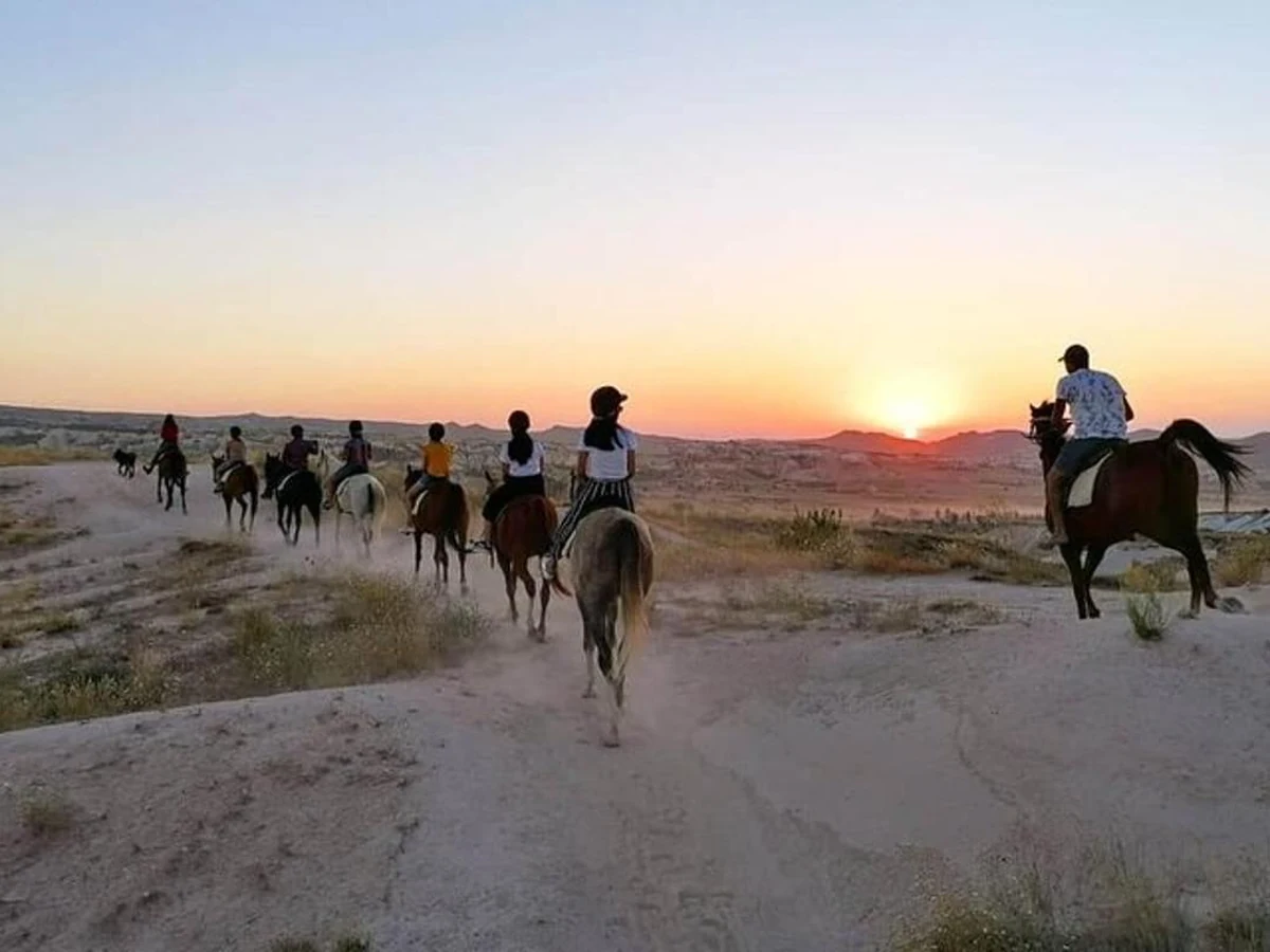 Horse riders returning along a Cappadocia trail as the sun sets