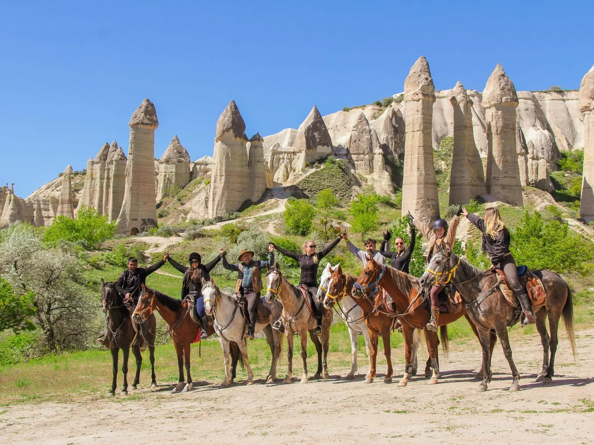 Horse riding tour group posing in front of Cappadocia fairy chimney formations