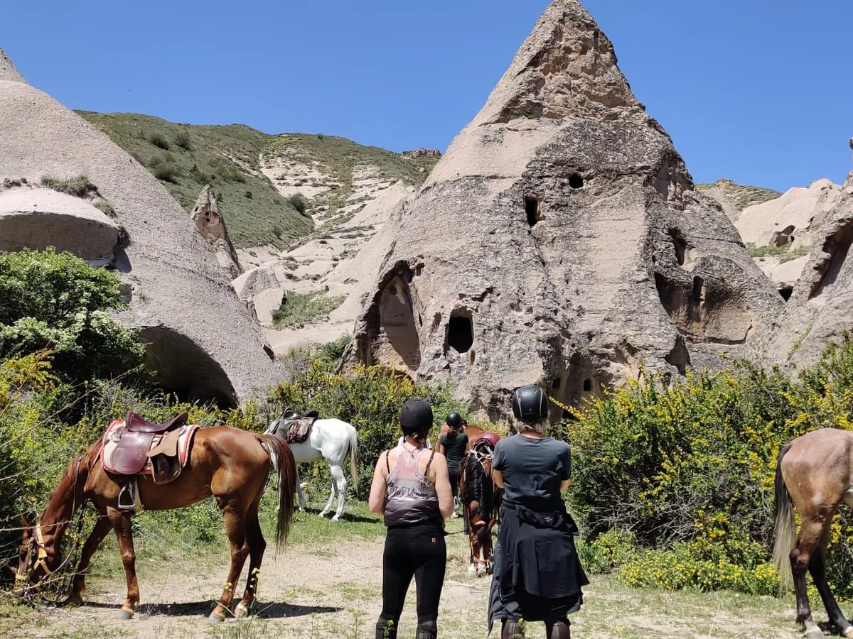 Horse riding tour guests stopping near historic cave churches in Cappadocia
