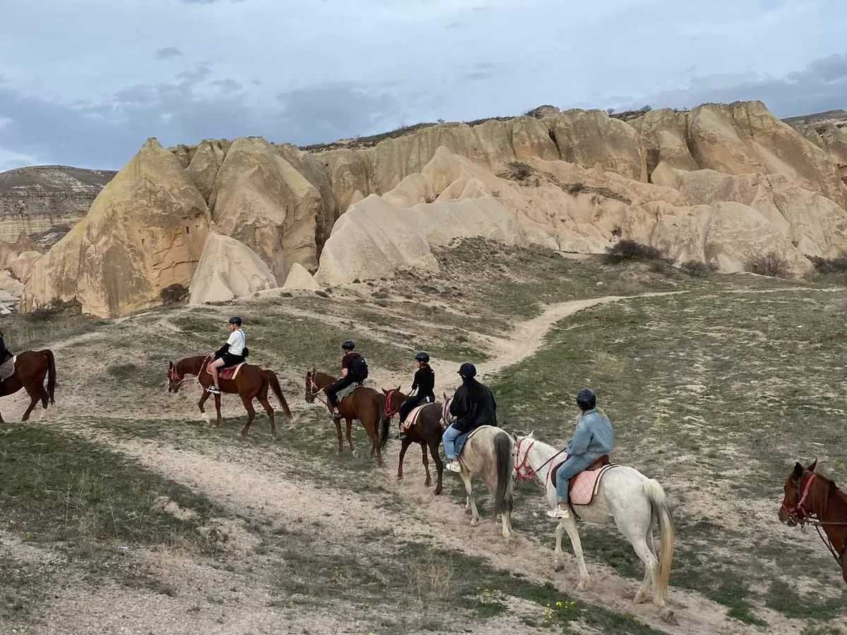 Horseback safari group riding along a rugged Cappadocia mountain trail