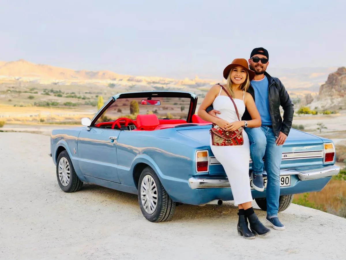 Couple posing with a blue vintage convertible during a Cappadocia sightseeing tour