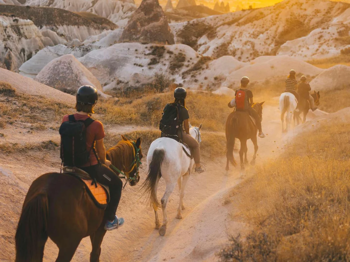 Travelers enjoying a horseback riding adventure at sunrise in Cappadocia