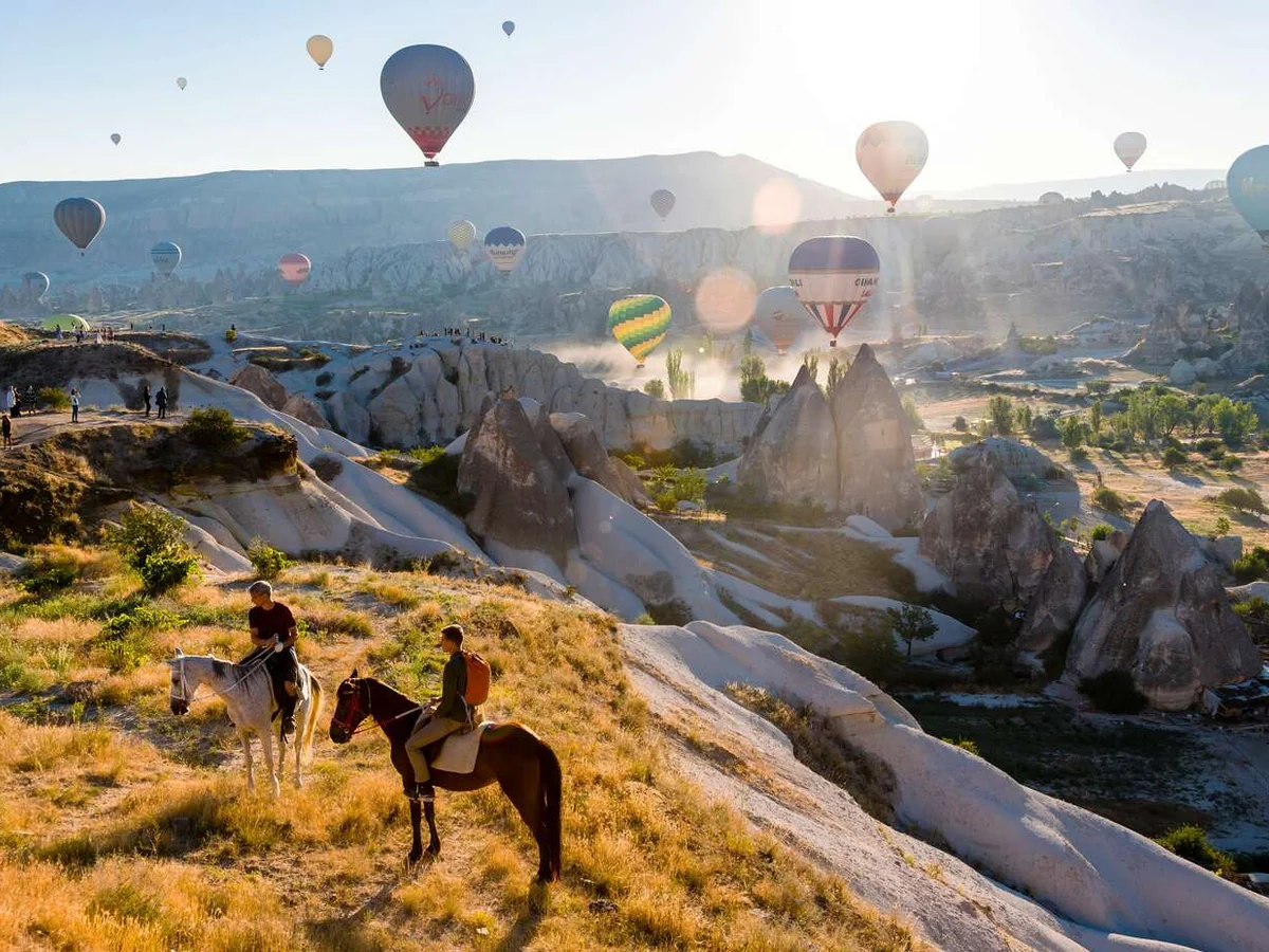 Horse riders touring Cappadocia as the sun rises over the valleys