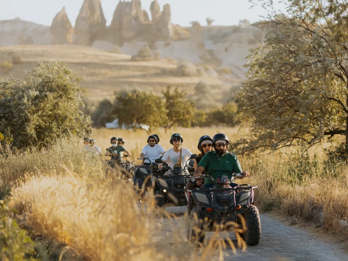 Helmeted riders following an off-road trail through the Cappadocia landscape