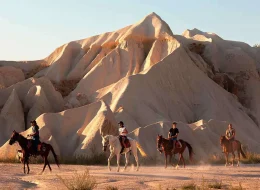 Horse riders crossing Cappadocia valleys during a sunset horse riding tour