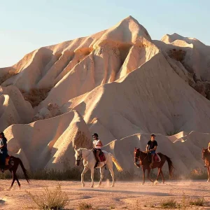 Horse riders crossing Cappadocia valleys during a sunset horse riding tour
