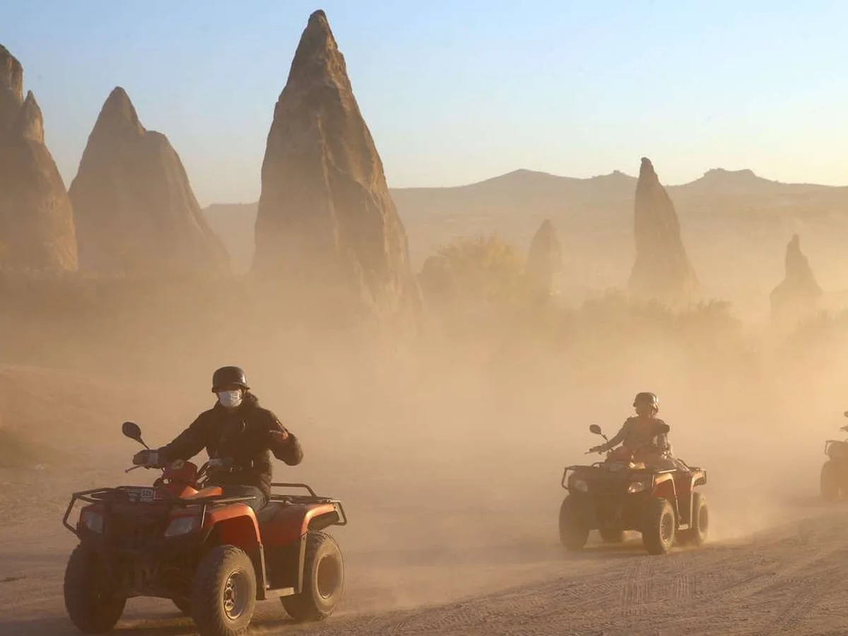Quad bike group riding through Cappadocia rock formations during golden hour