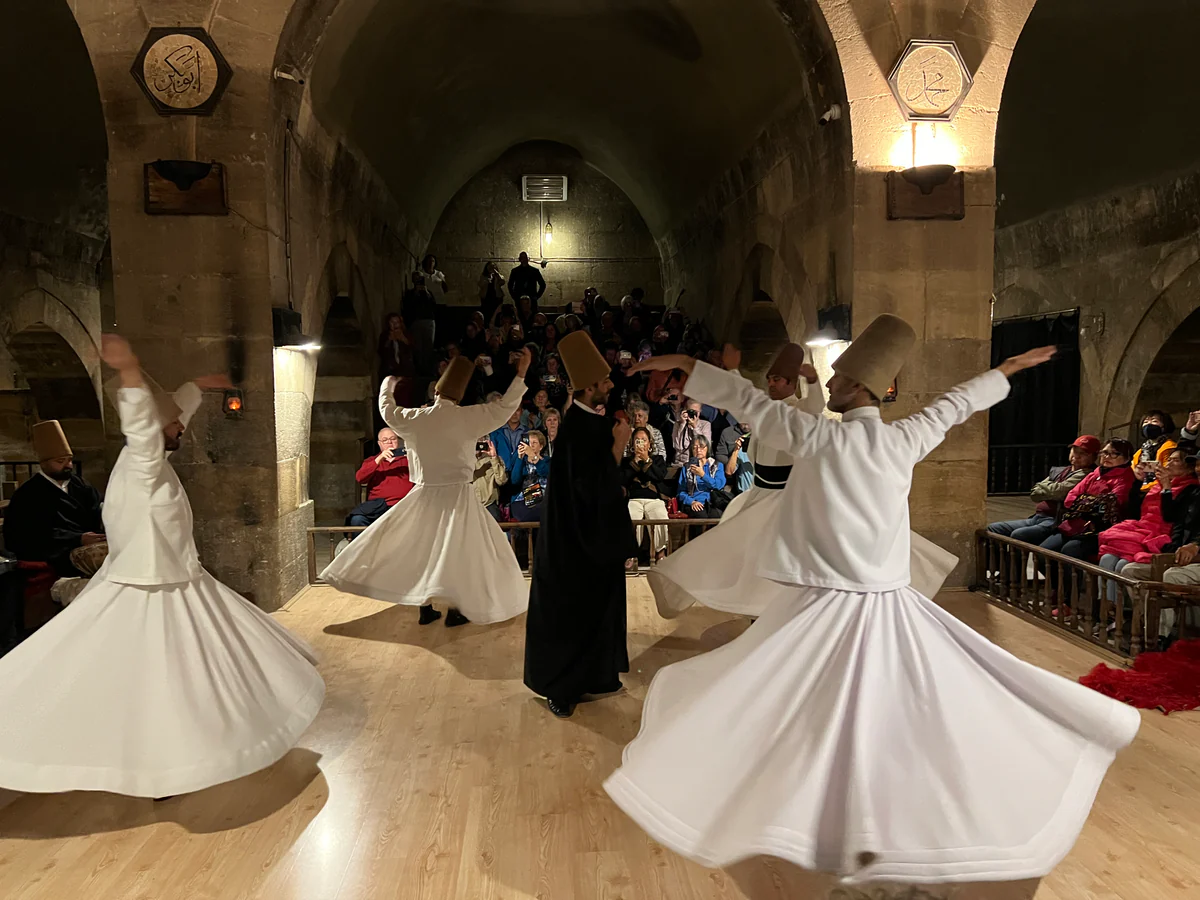 Whirling dervishes performing for visitors inside a Cappadocia caravanserai