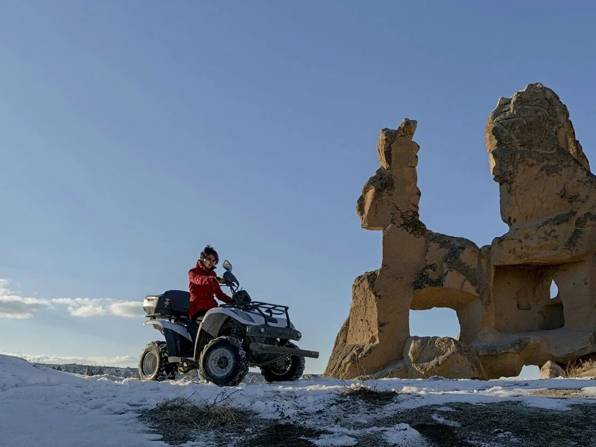 ATV rider exploring snow-covered Cappadocia rock formations in winter