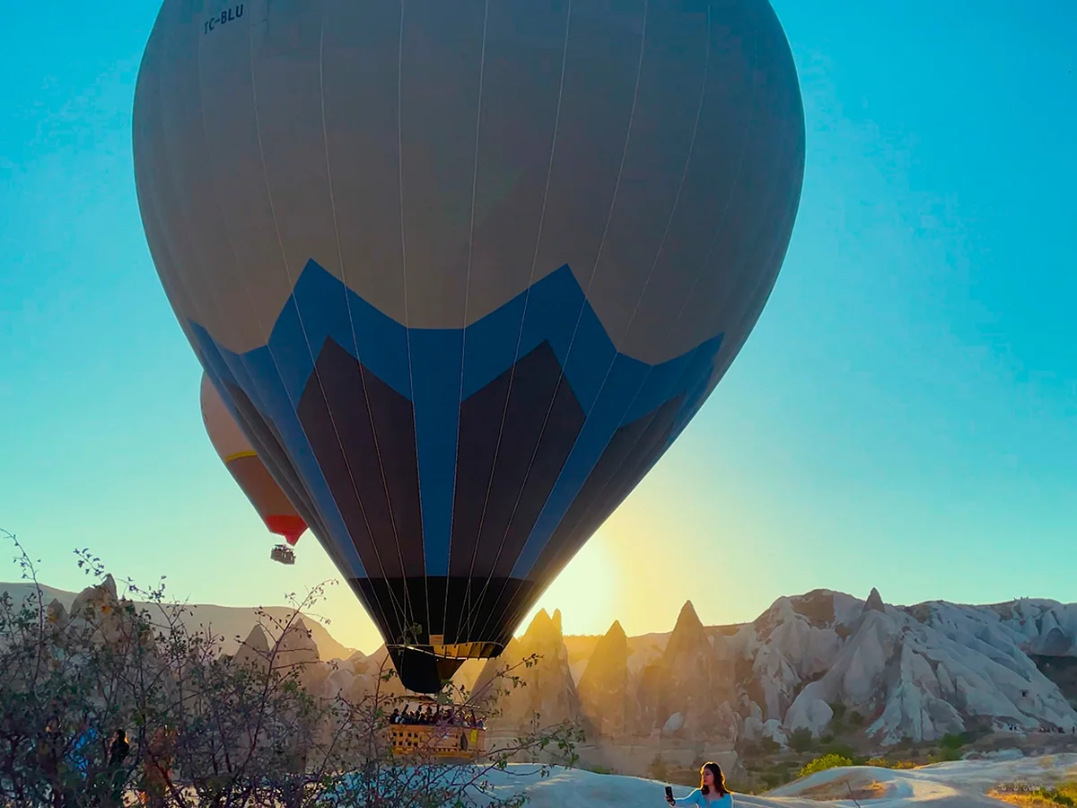 Hot air balloon lifting off at sunrise between the white rock ridges of Cat Valley