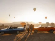 Blue and orange classic convertibles lined up during a Cappadocia balloon sunrise