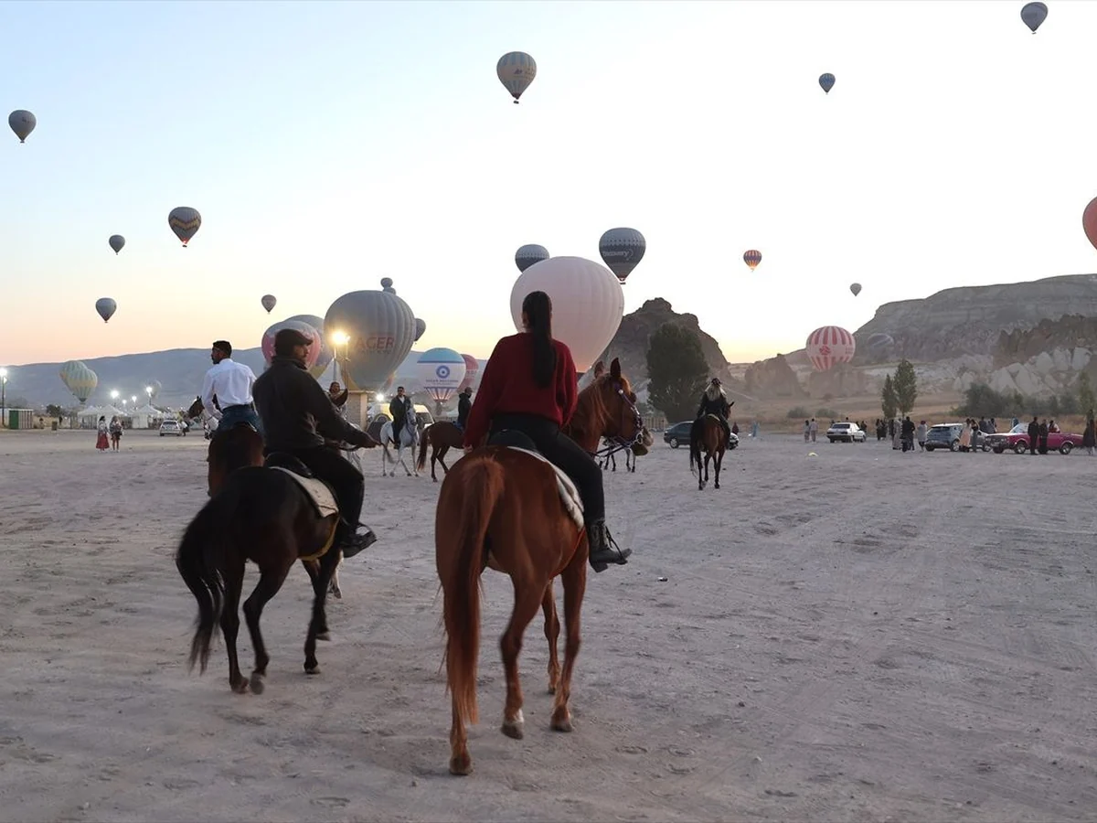 Guests following a guide on horseback during sunrise in Cappadocia