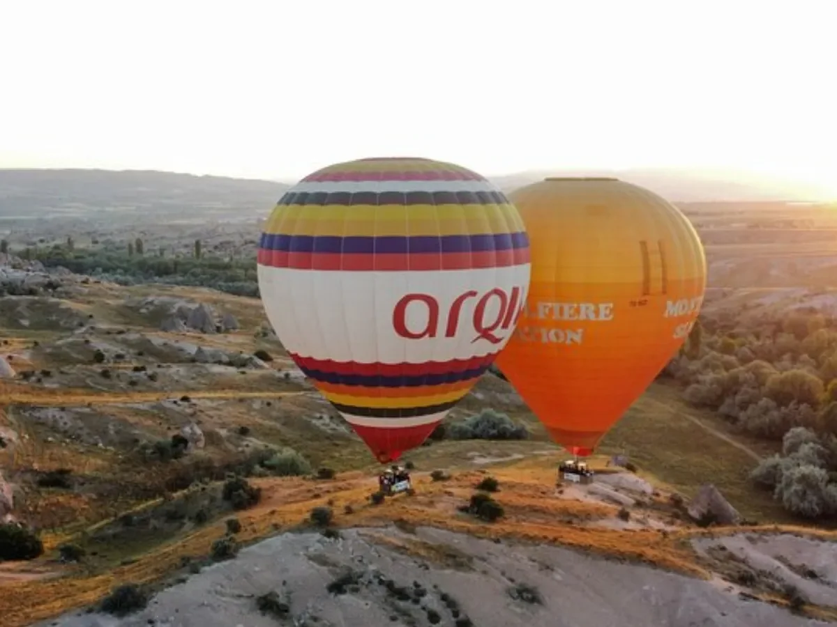 Two hot air balloons floating over the Cat Valley landscape in Cappadocia