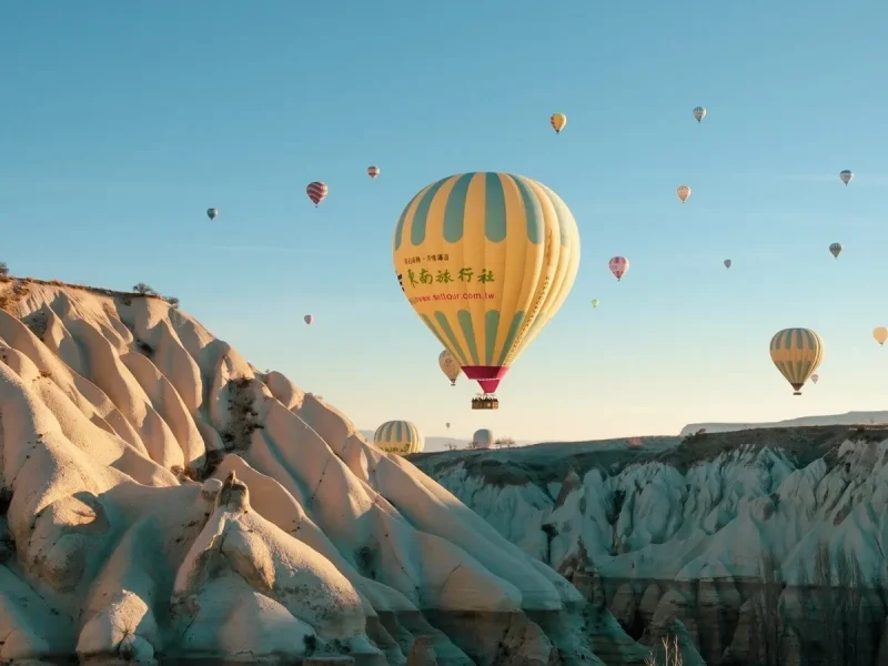 Peaceful hot air balloon floating over Cappadocia rock cliffs