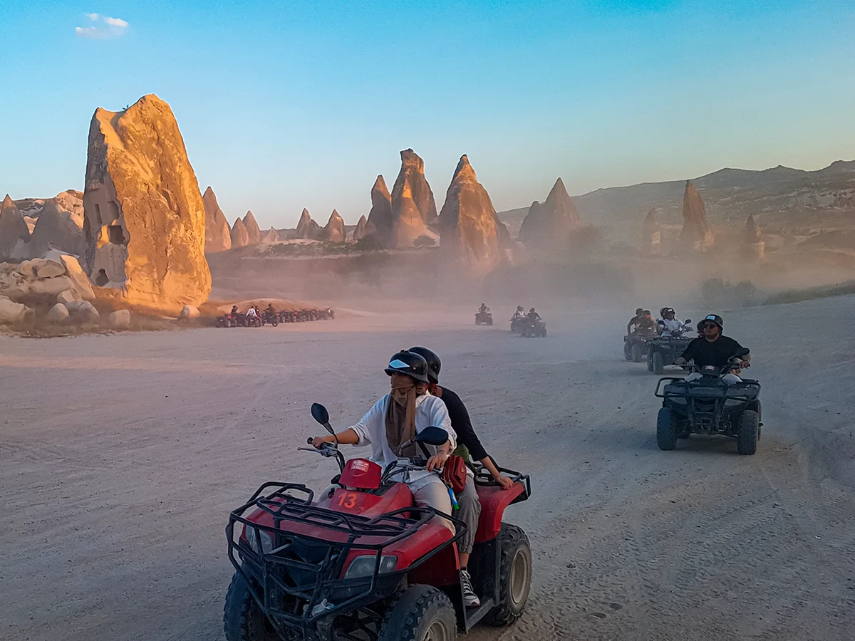 Quad bike riders exploring dramatic rock formations in a Cappadocia valley