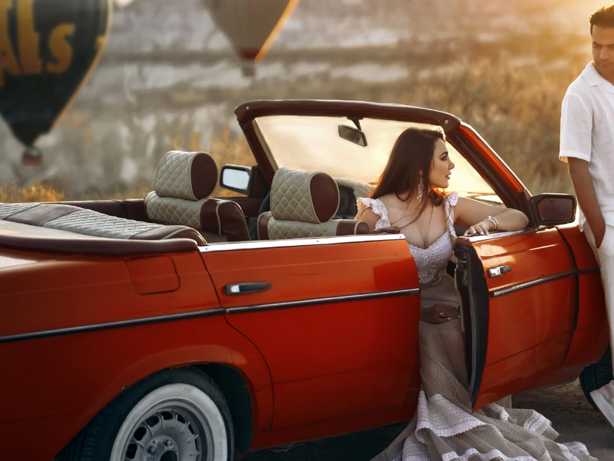 Woman posing in a red convertible vintage car during a Cappadocia balloon photoshoot
