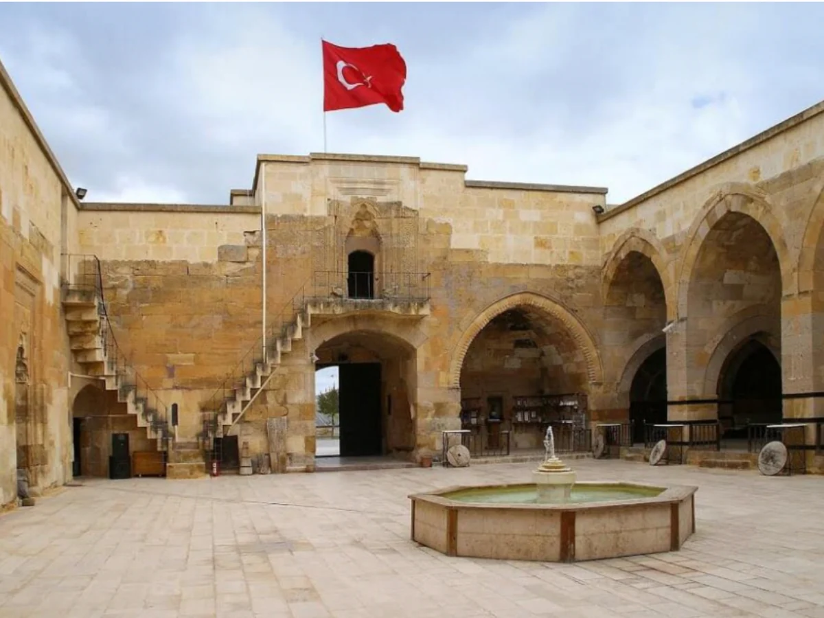 Historic courtyard of Saruhan Caravanserai in Cappadocia beneath the Turkish flag