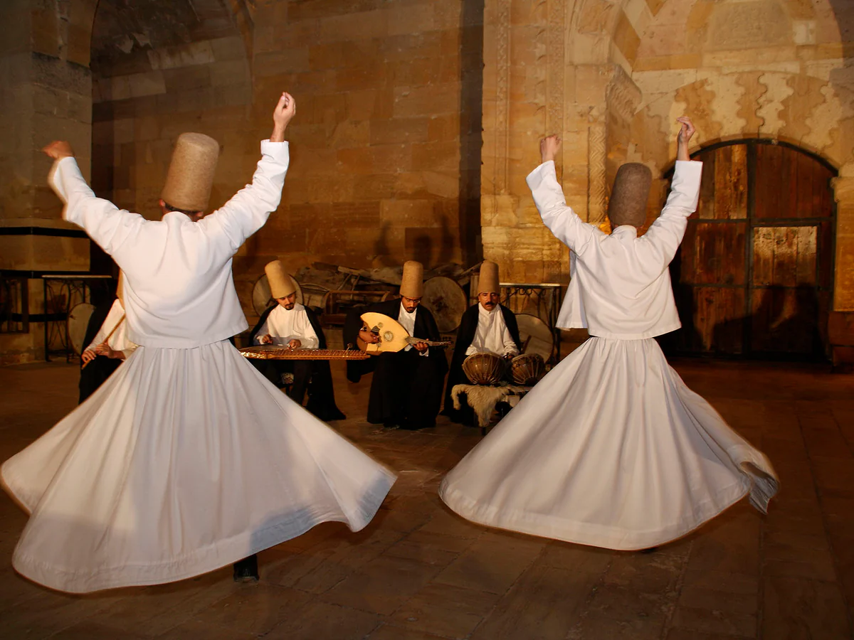 Two Sema dancers whirling inside a historic stone venue in Cappadocia