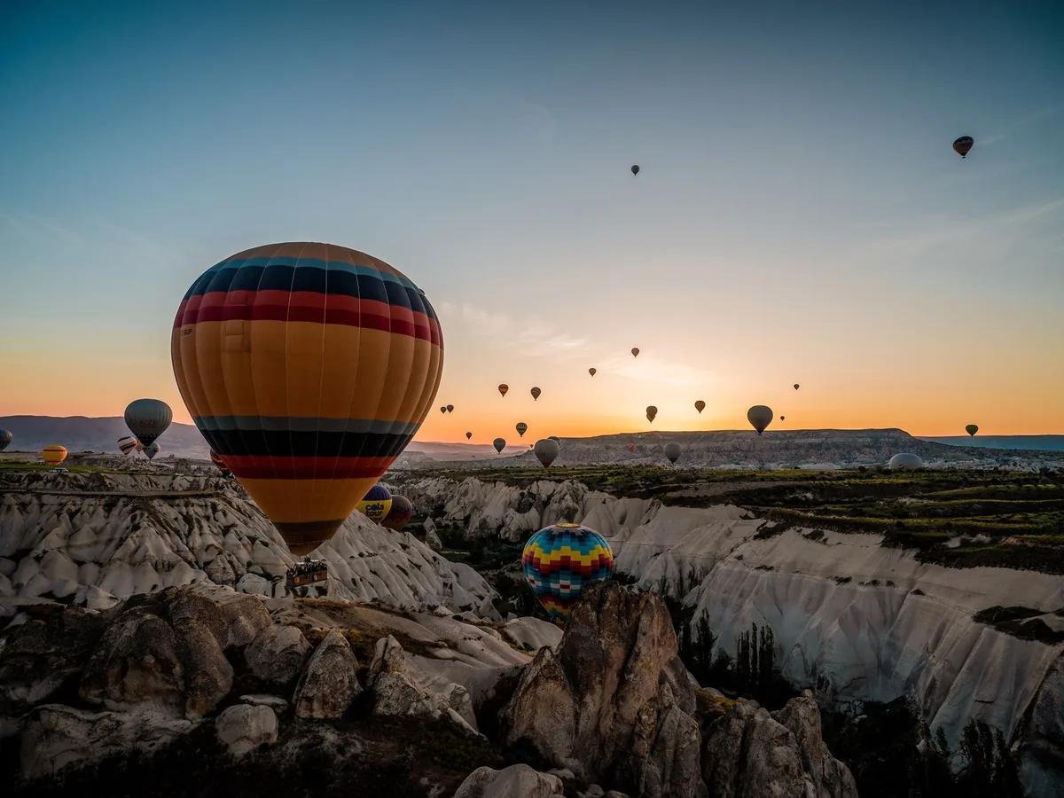Single hot air balloon floating over Göreme valley