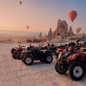 ATVs lined up for a Cappadocia sunrise tour with hot air balloons overhead