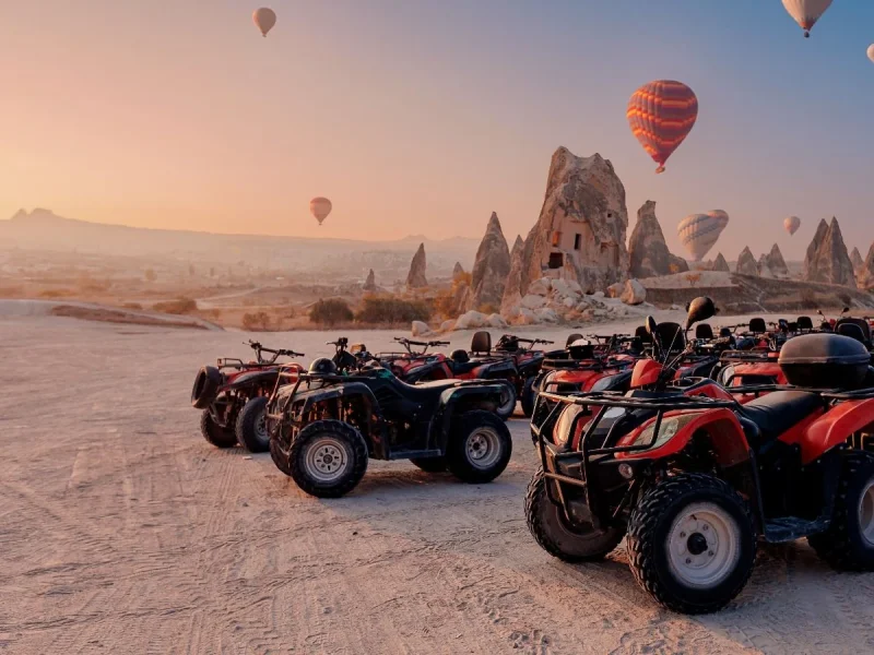 ATVs lined up for a Cappadocia sunrise tour with hot air balloons overhead