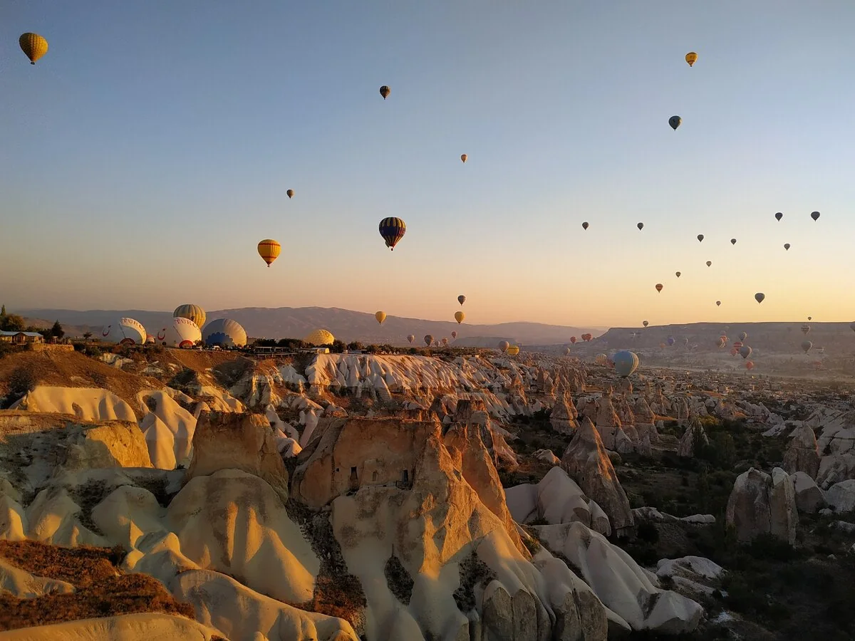 Sunrise balloons over Cappadocia rock valleys