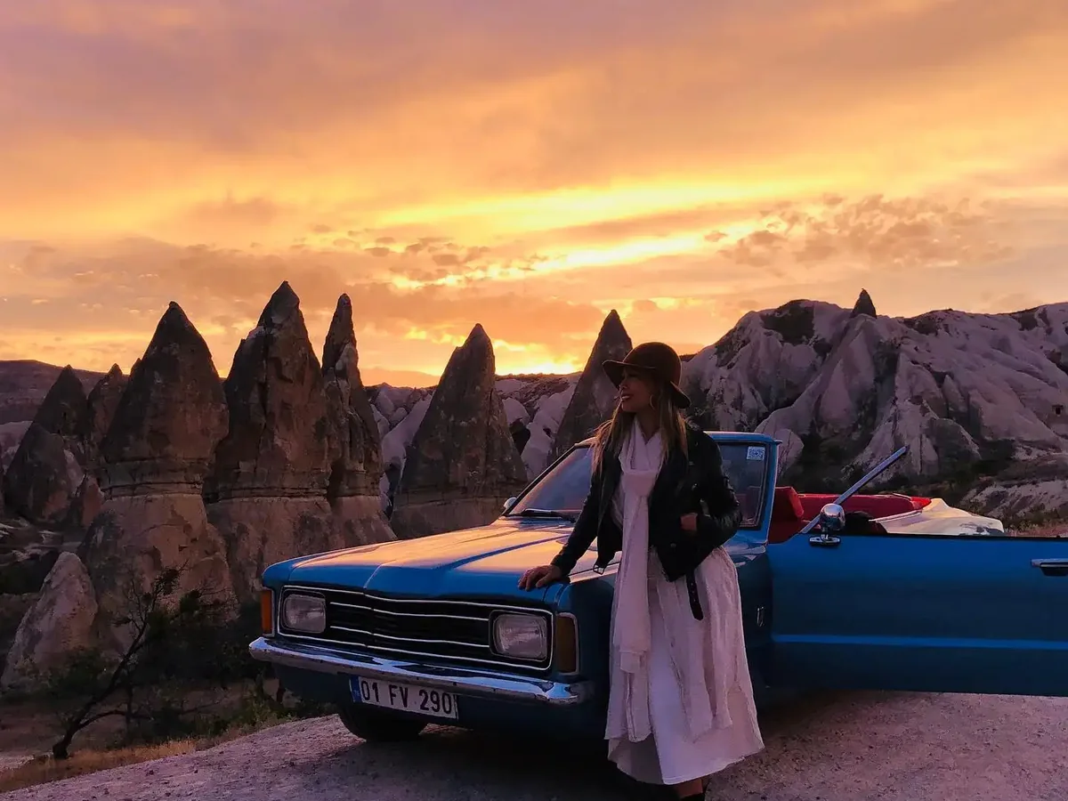 Couple beside a classic car under a colorful Cappadocia sunset