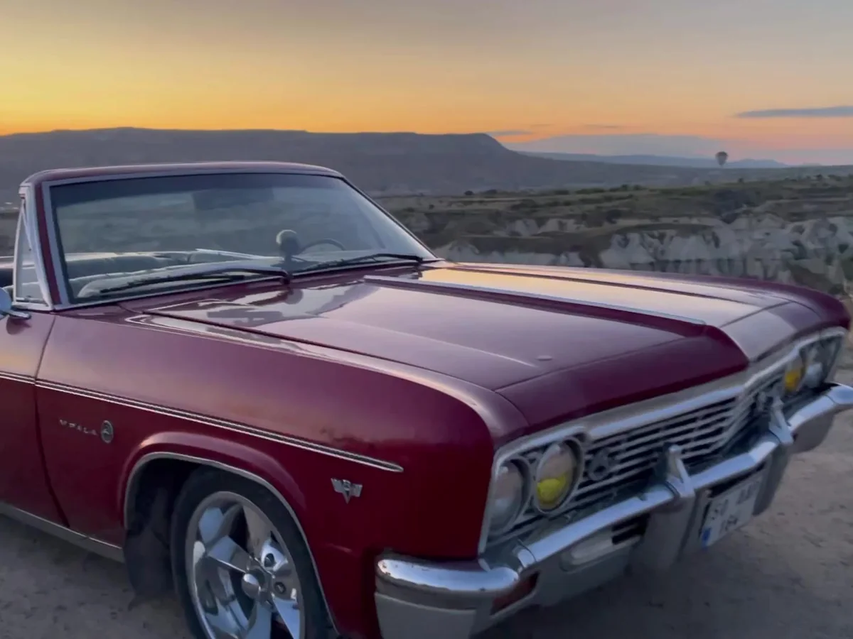 Red vintage convertible overlooking the Cappadocia valleys at sunset